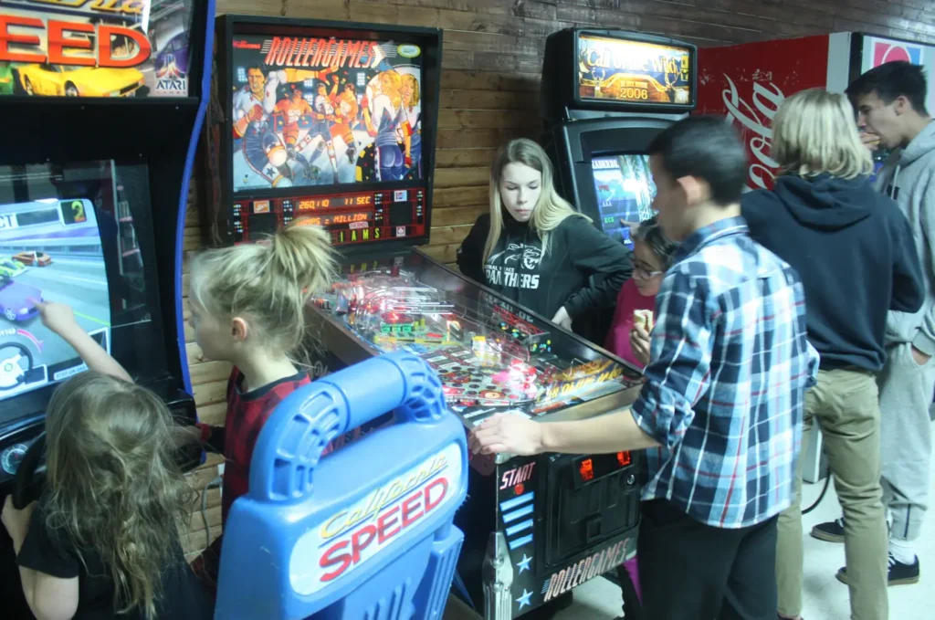 Children and teens playing pinball and arcade racing games