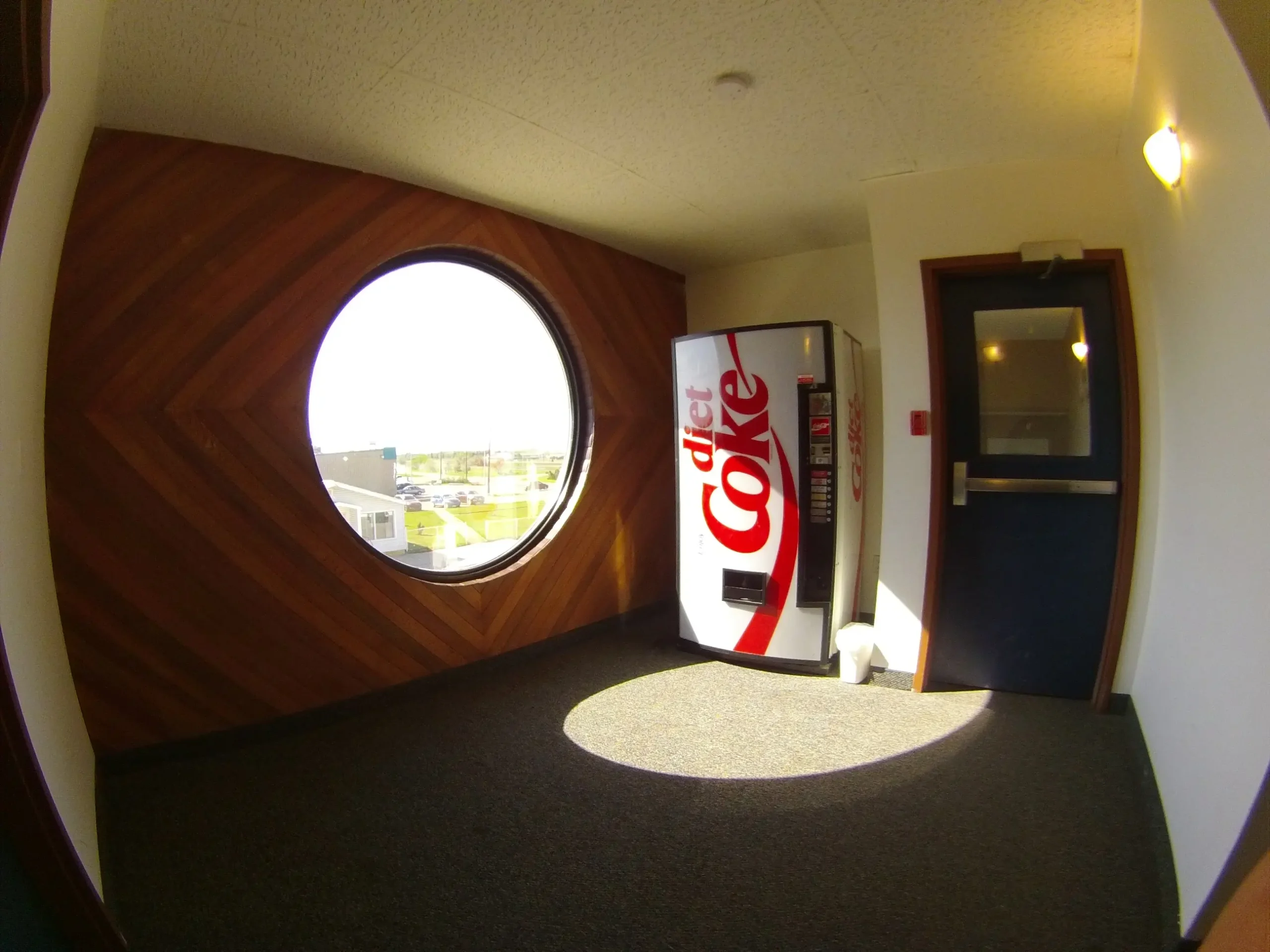Circular window, wooden panel wall, Diet Coke vending machine