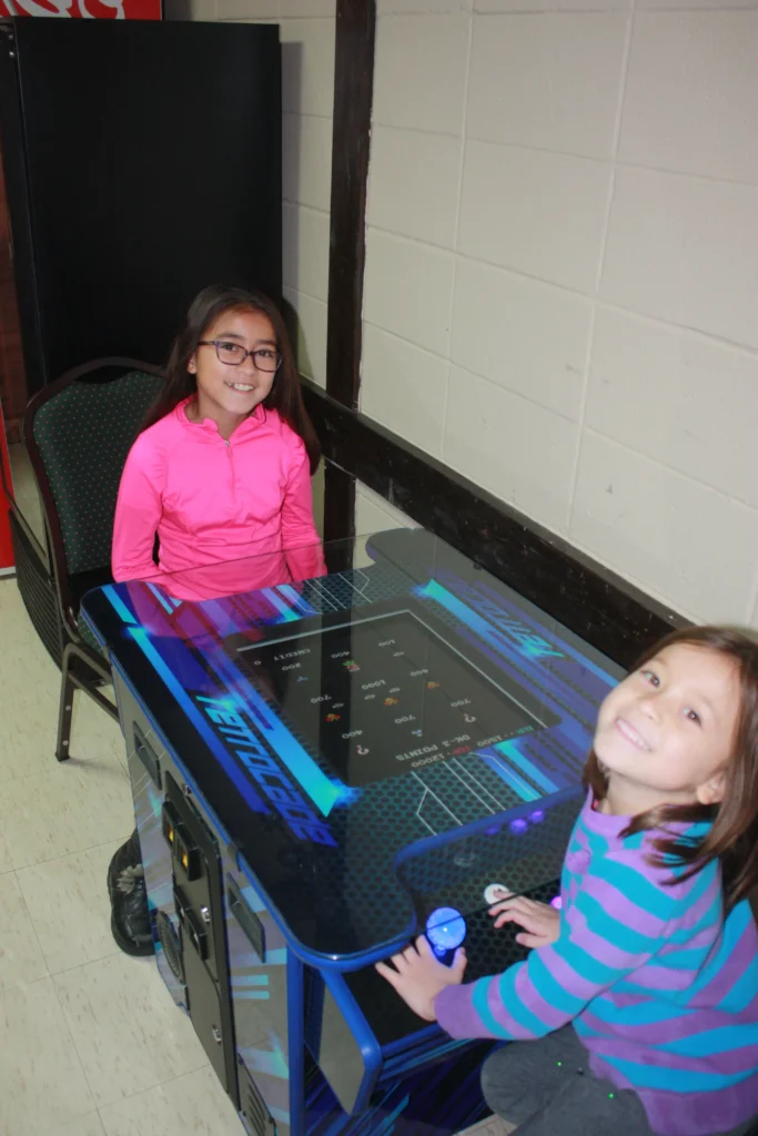 Girls smiling, playing an arcade game