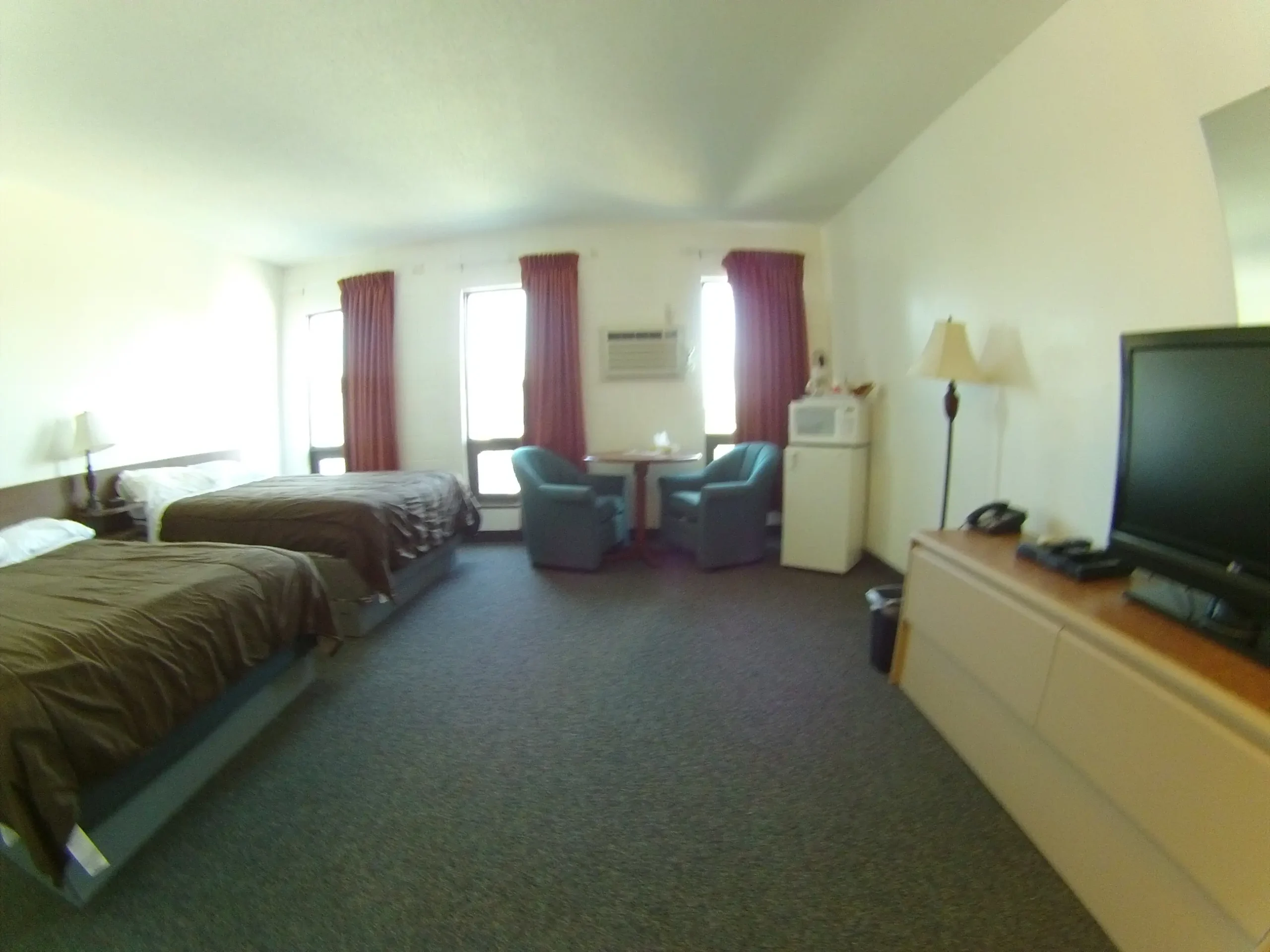Hotel room with two beds, table, chairs, TV, and mini-fridge