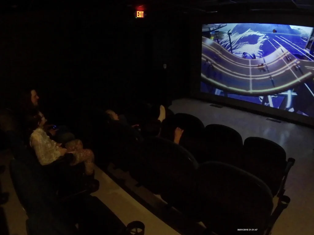 People watching a racing game in a mini-cinema