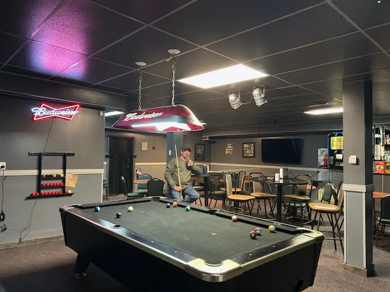 Person sitting by a pool table in a dimly lit room