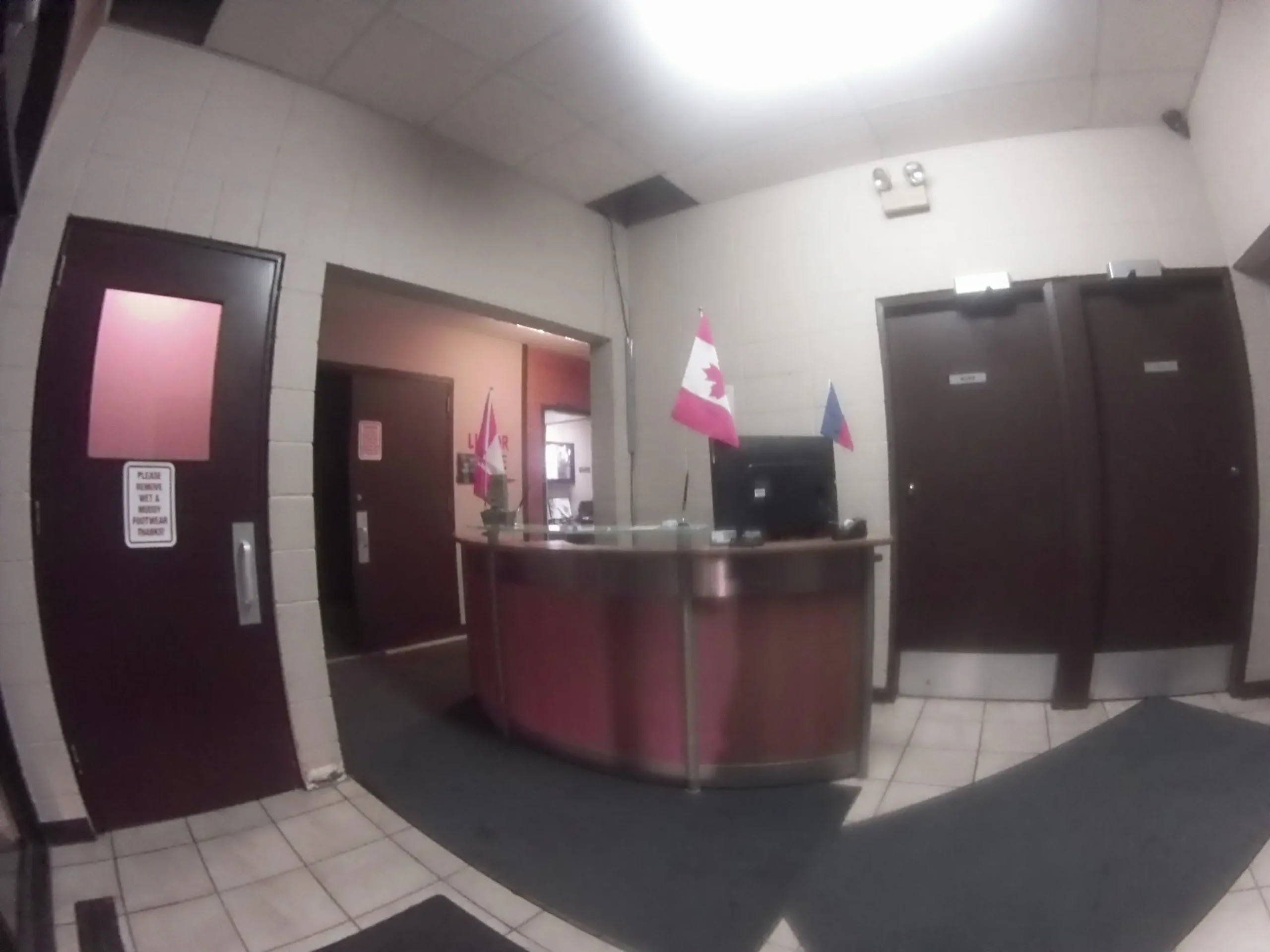 Reception desk with laptop, Canadian flag, and doors