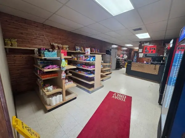 Store interior with shelves, brick walls, red rug, and counter