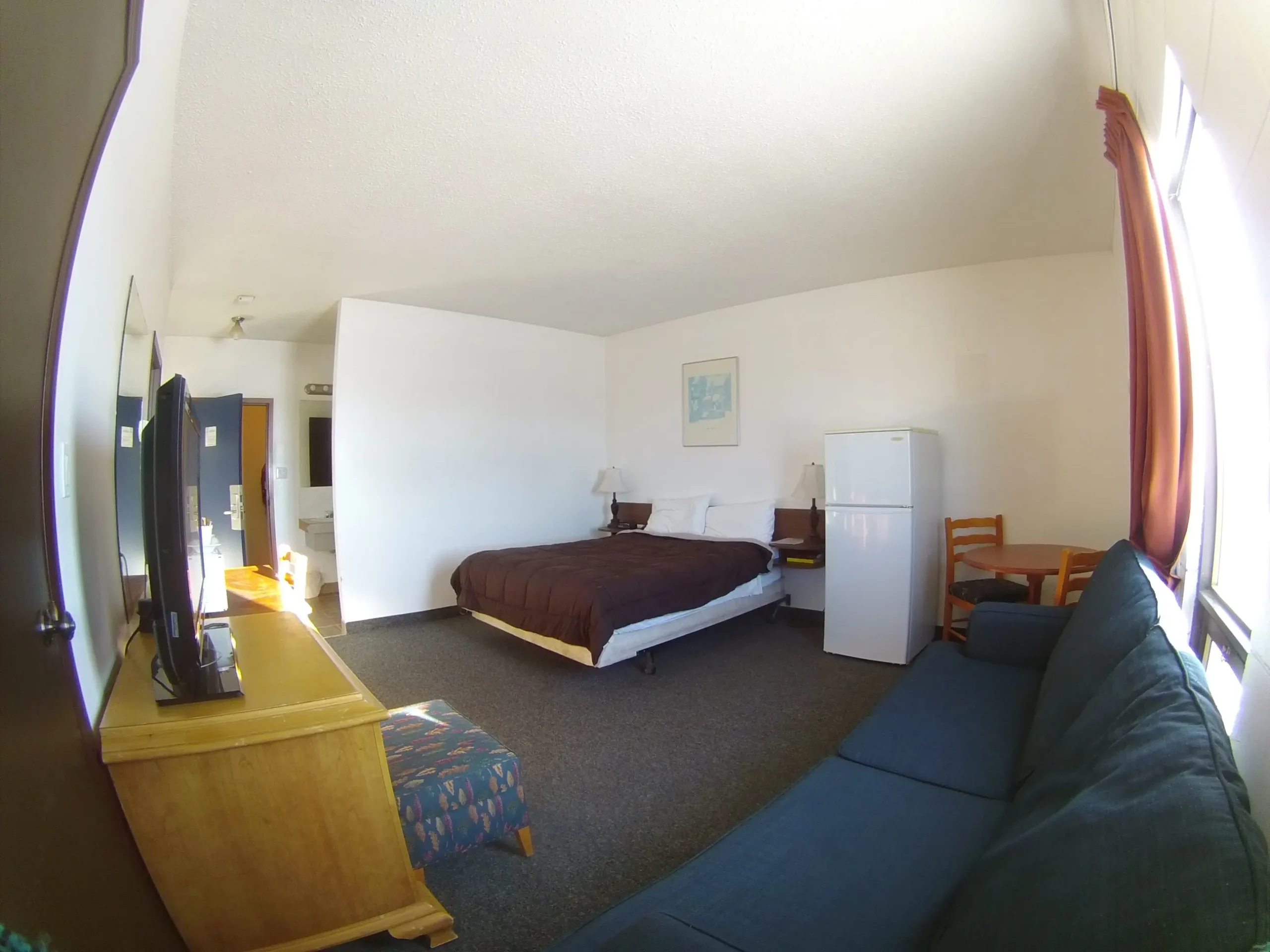 hotel room in Rycroft with a bed, blue sofa, refrigerator, and TV